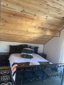 1 dormitorio con 1 cama con techo de madera en Acasa la Tulucu, en Bîrsana