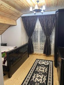 a bedroom with a bed and a window with curtains at Acasa la Tulucu in Bîrsana +12 photos