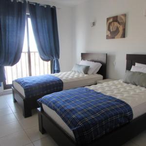 - une chambre avec 2 lits et une fenêtre avec des rideaux bleus dans l'établissement BCV - Private Villas with Pools Dunas Resort 7, 27, and 53, à Santa Maria