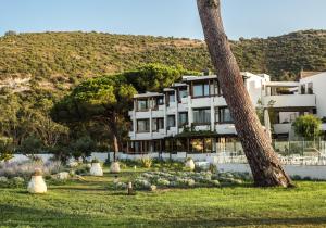 a large white building with a hill in the background at Hôtel La Roya in Saint-Florent