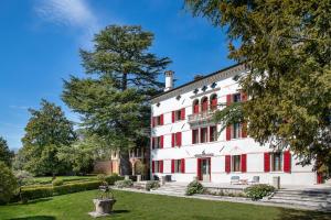 uma vista exterior de um grande edifício branco com persianas vermelhas em Villa Premoli - Agriturismo di charme em Cavaso del Tomba