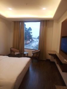 um quarto de hotel com uma cama e uma grande janela em Namastasya em Solan
