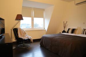 a bedroom with a bed and a chair and a window at Bar-Bistro-Hotel DOK in Steenbergen