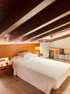 a bedroom with a large white bed and a desk at María Pacheco Hotel Boutique in Avila