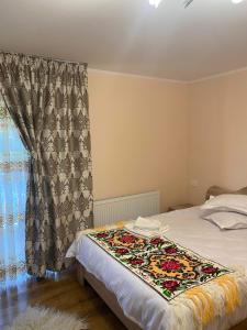 a bedroom with a bed with a blanket on it at Acasa la Tulucu in Bîrsana