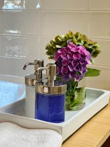 a bathroom sink with a vase of purple flowers at Garden House in Detmold