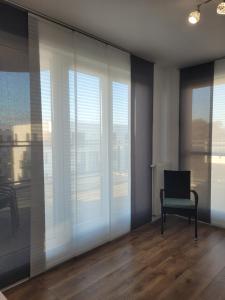 a room with a chair and a window with white blinds at Nowoczesny, rodzinny apartament z widokiem na morze in Puck
