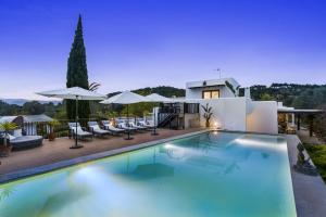 una piscina con sillas y sombrillas frente a una casa en Ravishing Ibiza Villa Cel Blau 9 Bedrooms Private Pool and Beautiful Country Views Santa Eulalia, en Santa Eulària des Riu