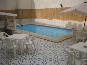 a swimming pool with tables and chairs in a restaurant at Hotel Mezri in Monastir