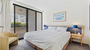 a bedroom with a bed and a chair and a window at Boathouse Premium Apartment 102 in Tea Gardens
