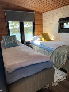 two beds in a room with a window at Beach Cottage in Hanko