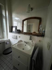 a white bathroom with a sink and a mirror at Im alten Pastorat in Grevenbroich