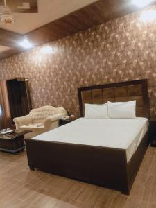 Royal Fort Executive Hotel Gulberg في لاهور: غرفة نوم بسرير وكرسي وأريكة