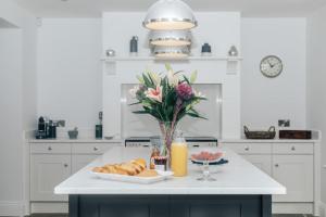 a white kitchen with a table with bread and a vase of flowers at Woodvale Retreat in Harpsden
