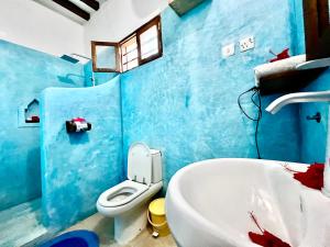 a blue bathroom with a toilet and a sink at Chikachika Beach B&B in Nungwi