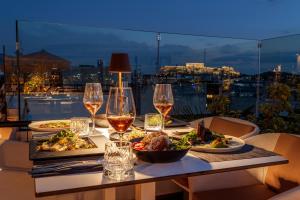 einen Tisch mit zwei Teller Essen und Gläsern Wein in der Unterkunft Brown Acropol, a member of Brown Hotels in Athen