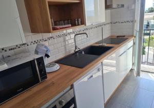 a white kitchen with a sink and a microwave at Escapade Montesquieu in Perpignan