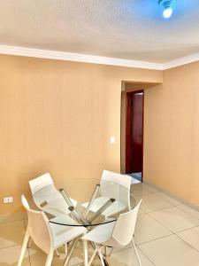 a dining room with a glass table and white chairs at Apartamento 3 quartos Bueno com 2 garagens in Goiânia