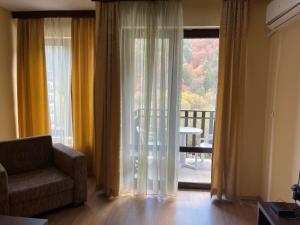 Una sala de estar con una silla y una ventana grande. en Мия 2 Спа хотел Свети Спас, en Velingrad