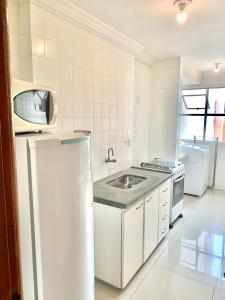 a white kitchen with a sink and a refrigerator at Apartamento 3 quartos Bueno com 2 garagens in Goiânia
