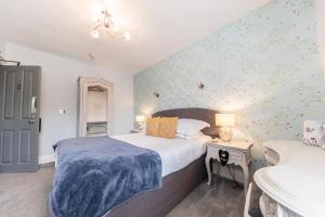 a bedroom with a bed with a blue blanket on it at Heidi's Grasmere Lodge in Grasmere