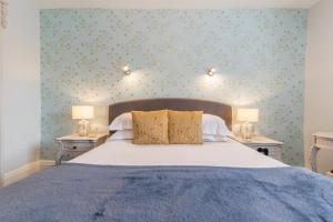 格拉斯米爾的住宿－Heidi's Grasmere Lodge，一间卧室配有一张床和两张带台灯的桌子。