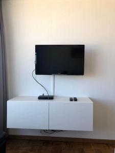 a flat screen tv on top of a white cabinet at Studio met frontaal zeezicht in Ostend