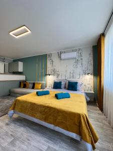Un dormitorio con una gran cama amarilla con almohadas azules en AAB Studio Central en Piatra Neamţ