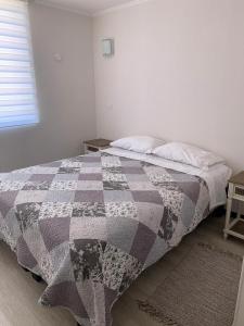 a bed with a checkered blanket in a bedroom at Departamento Pacífico 2800-Reserva Mínima de 3 días in La Serena