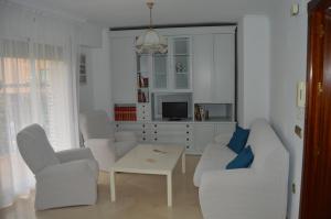 un soggiorno con sedie bianche e una TV di Apartamento en pleno centro de Córdoba a Cordoba