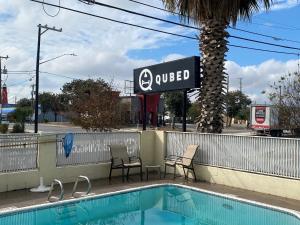 a swimming pool with two chairs and a sign at Qubed San Antonio in San Antonio