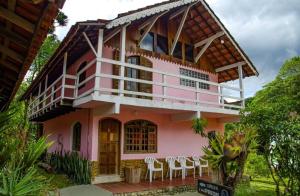 uma casa cor-de-rosa com cadeiras à frente. em Pousada Chalés do Lago em Visconde de Mauá