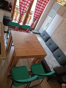 - un salon avec une table en bois et des chaises vertes dans l'établissement la dryade chinaillon, au Grand-Bornand