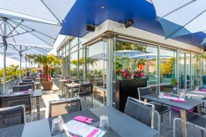 um restaurante com mesas, cadeiras e guarda-sóis em Sedartis Swiss Quality Hotel em Thalwil