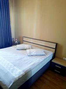 a bedroom with a bed with white sheets and a blue curtain at Apartament - Axis palace saburtalo in Tbilisi City