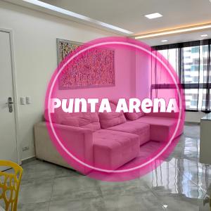 un sofá rosa en una habitación con un cartel de agenda rosa en Apto Frente ao Mar Asturias, en Guarujá