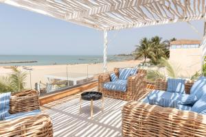 eine Terrasse mit Stühlen, einem Tisch und dem Strand in der Unterkunft beachhouse MIMA in Saly Portudal