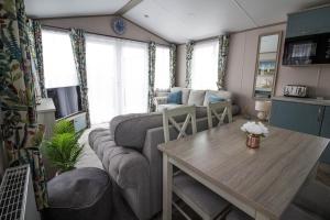ein Wohnzimmer mit einem Sofa und einem Tisch in der Unterkunft Stunning Caravan With Wifi At Azure Seas Nearby The Beautiful Beach Ref 32057az in Lowestoft