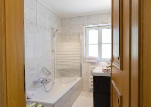 Baño blanco con bañera y lavamanos en Haus Mayerhofer, en Sankt Gilgen
