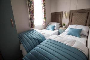 two beds in a small room with blue pillows at Stunning Caravan With Wifi At Azure Seas Nearby The Beautiful Beach Ref 32057az in Lowestoft