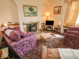 a living room with purple furniture and a fireplace at Low Skibeden Cottage in Skipton