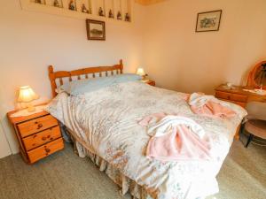 a bedroom with a bed with a dresser and a table at Low Skibeden Cottage in Skipton
