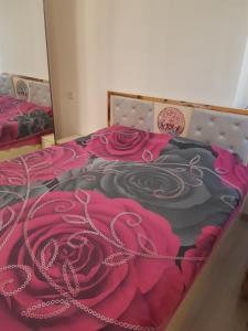 a bedroom with a bedspread with pink roses on it at Holiday House Spiridi in Batumi