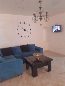 a living room with a blue couch and a clock on the wall at Holiday House Spiridi in Batumi