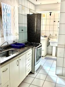een witte keuken met een wastafel en een fornuis bij Apartamento de 3 quartos 3 banheiros no melhor do bueno in Goiânia
