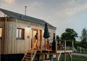 una pequeña casa de madera con terraza y sombrilla en Wohnwagon Paul - Autarkie erleben! - Tiny House en Oberschneiding