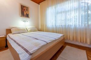 a bedroom with a bed and a large window at Apartments Hinic in Selce