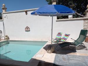 two chairs and an umbrella next to a swimming pool at Casale Oasi in Pozzallo