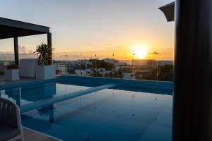 a swimming pool with the sunset in the background at New & Equipped Apartment Steps From The Beach With Pool Jacuzzi By Yeah in Playa del Carmen