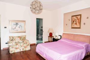 1 dormitorio con 1 cama, 1 silla y 1 lámpara de araña en Terrazza Angela, en Fiumefreddo di Sicilia